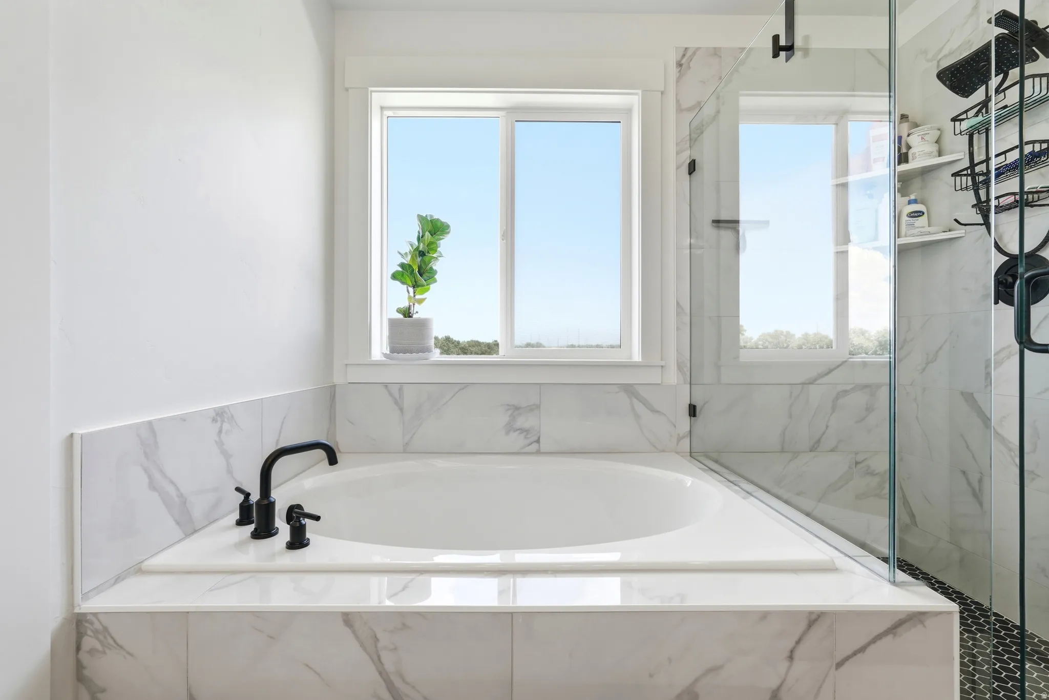 Built-in soaking tub featuring matte black fixtures and surrounding marble-look tile