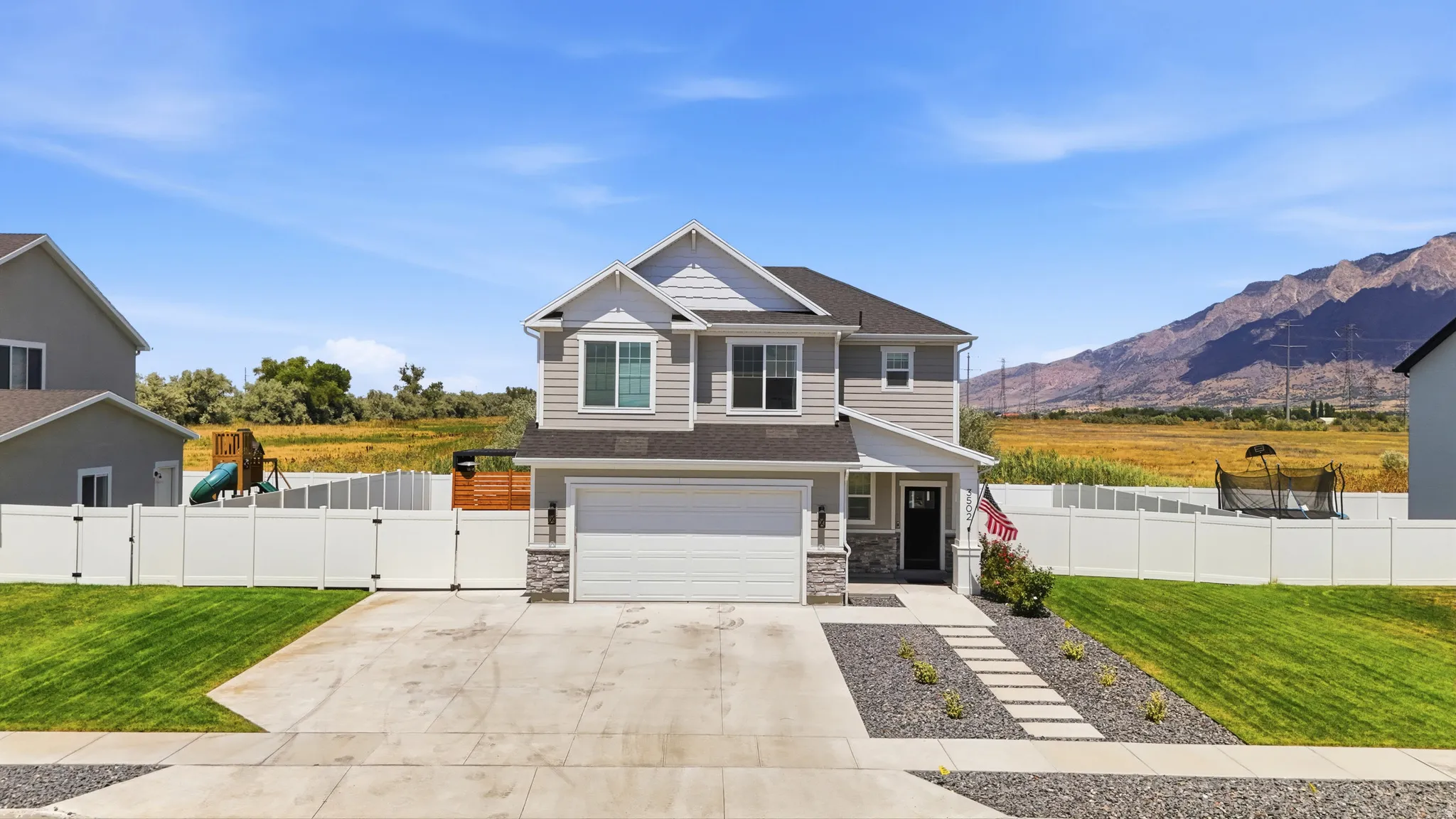 Two-story residence featuring light gray siding and stone accents
