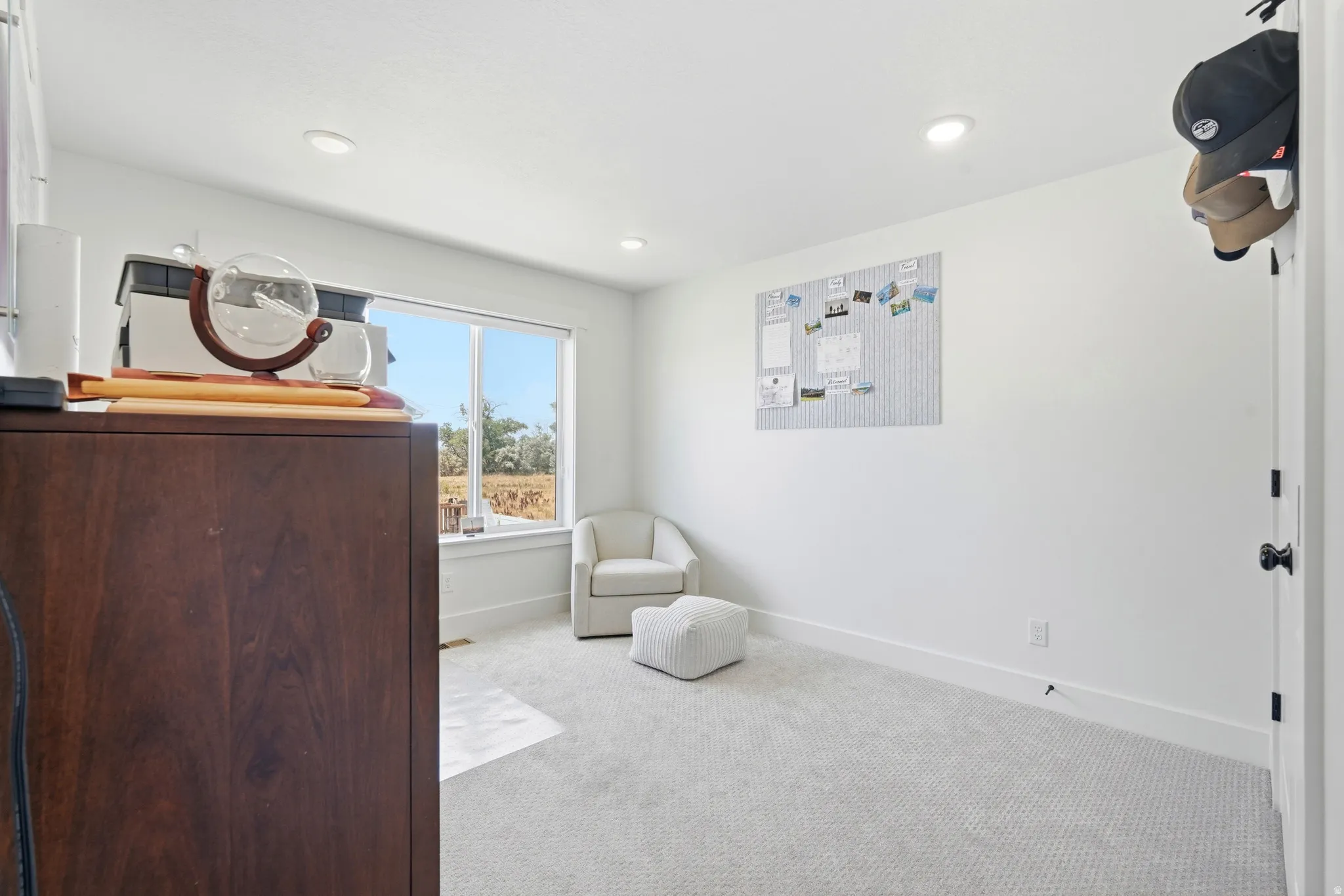 Bright room featuring a large window, recessed lighting, white walls, and light-toned patterned carpeting