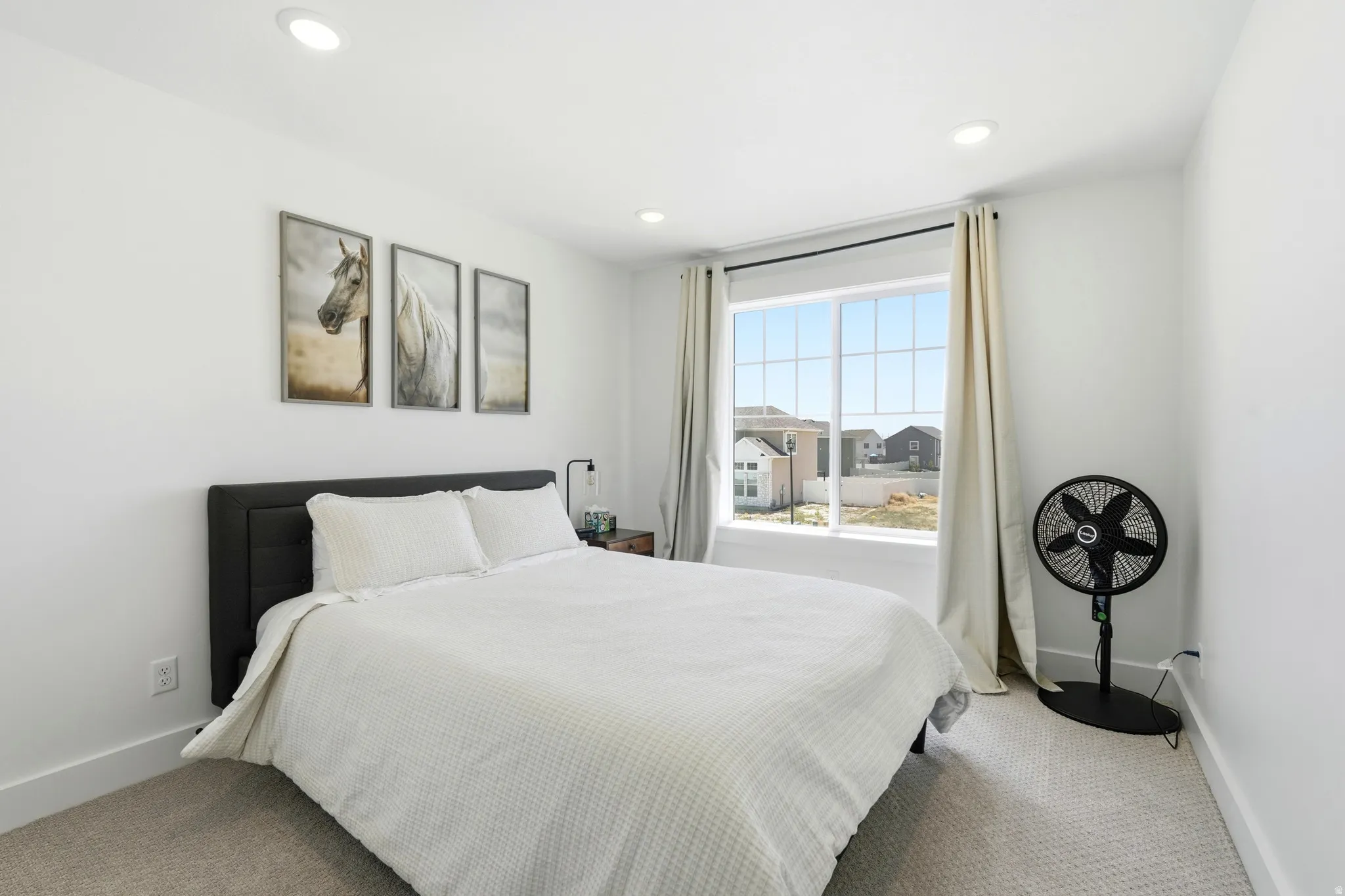 Carpeted room featuring a large window with white framing, recessed ceiling lighting, and crisp white walls