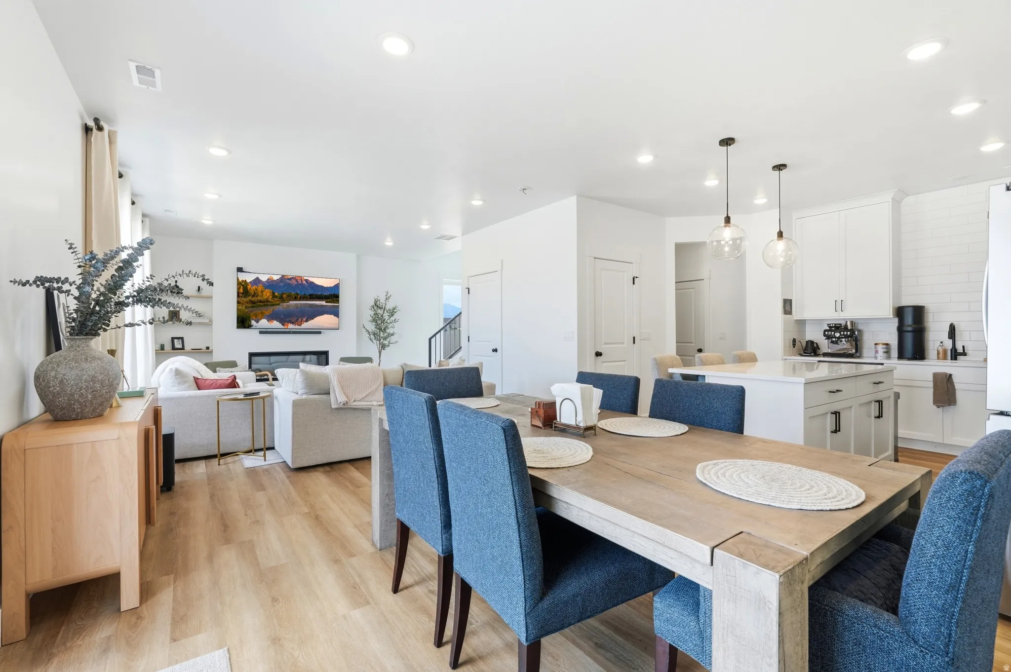 Open-concept living space featuring wood-finish flooring, recessed lighting, and a contemporary fireplace