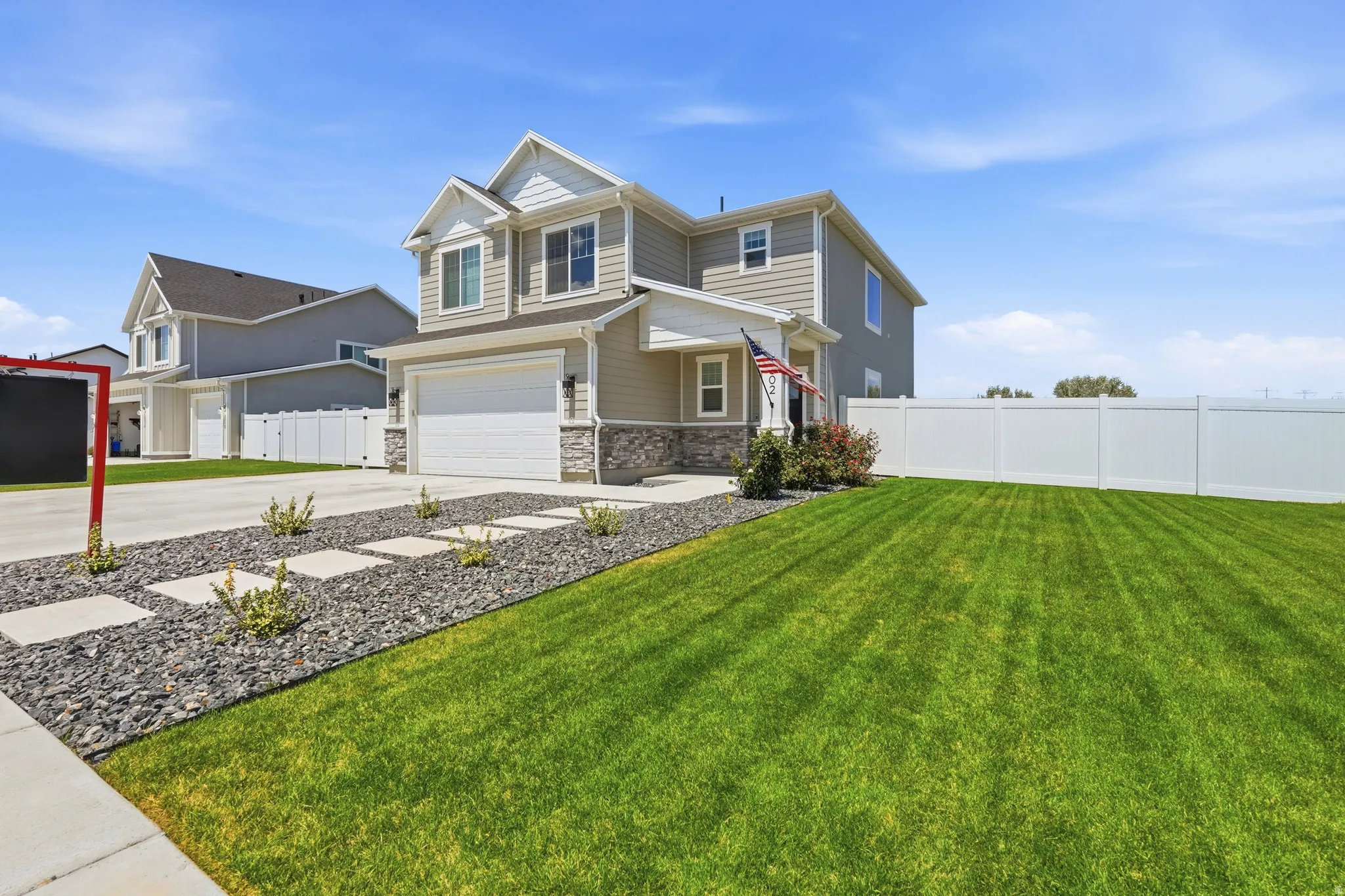Two-story residential structure featuring a two-car garage, stone veneer accents, and a covered front entry