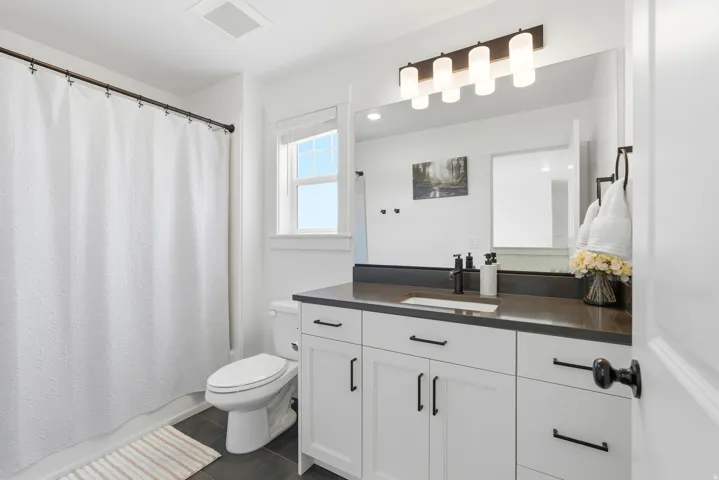 Bathroom featuring a white vanity with dark countertop, an integrated sink, and matte black hardware