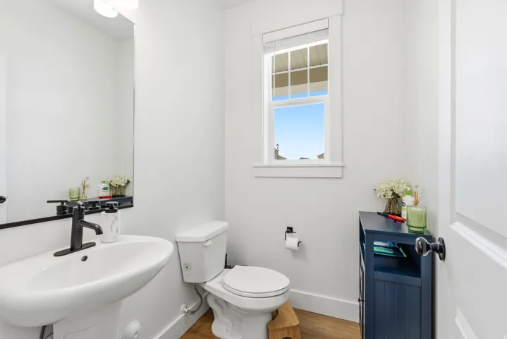 White pedestal sink with matte black faucet, wall-mounted mirror, and white wall sconce lighting