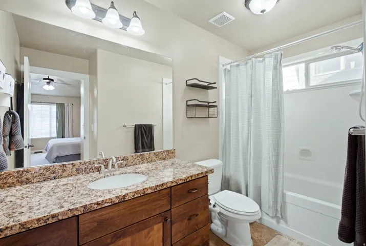 Bathroom featuring a wood-finish vanity with a granite-style countertop, undermount sink, and brushed nickel faucet