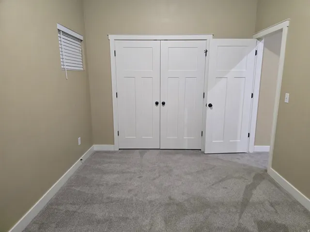 Neutral-toned walls complement plush grey carpeting