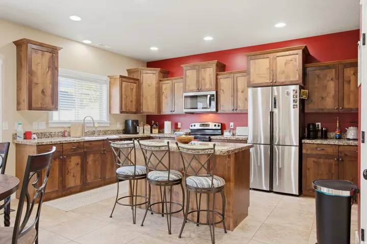 Kitchen featuring natural wood cabinetry, stone countertops, a stainless steel French door refrigerator, and a stainless steel over-the-range microwave