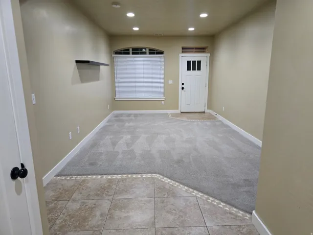 Recessed lighting, wood-paneled door, tiled entryway, arched window, and built-in shelving
