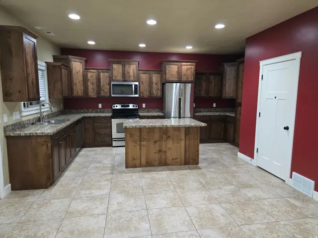 Kitchen featuring wood cabinetry, granite-style countertops, stainless steel appliances, a kitchen island, and recessed lighting
