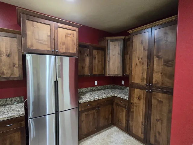 Kitchen featuring natural wood cabinetry, light-toned countertops, and a stainless steel refrigerator