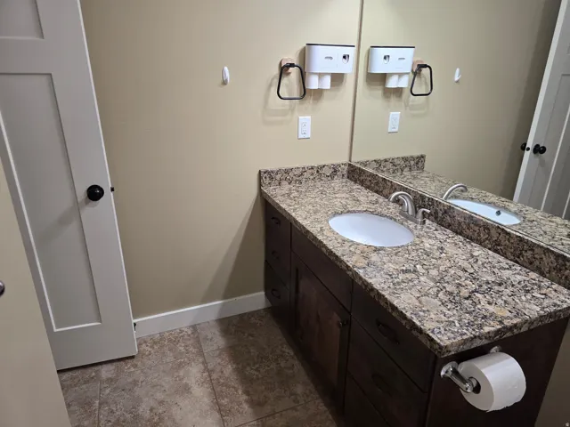 Dark wood-finish vanity with an undermount sink, granite countertop, and a large wall-mounted mirror