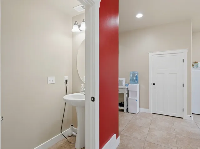 Pedestal sink featuring a wall-mounted vanity light and an oval mirror