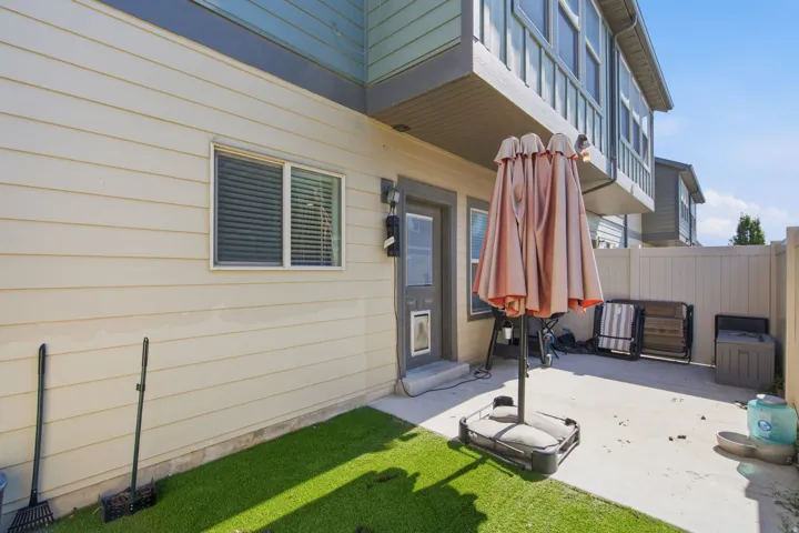 Outdoor concrete patio with a privacy fence and a patch of artificial turf