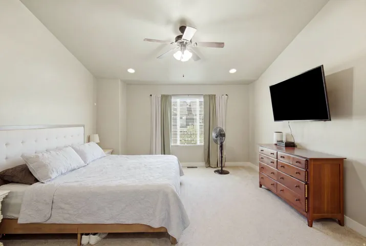 Spacious bedroom featuring neutral wall tones, recessed lighting, a ceiling fan, and carpeted flooring