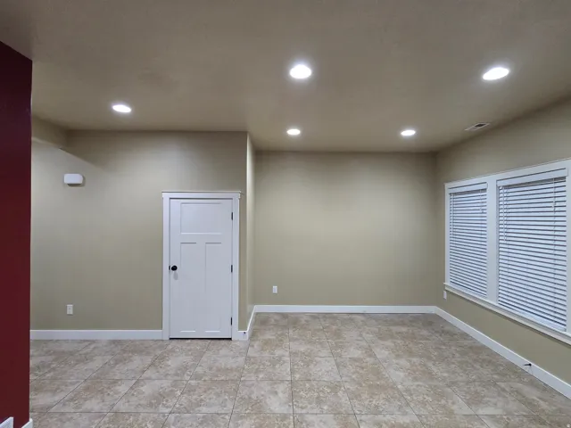 Recessed ceiling lighting, tiled flooring, multiple windows, white door with black hardware, and white trim
