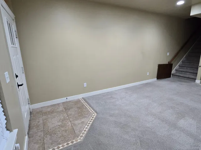 Recessed lighting illuminates neutral-toned walls, featuring a white paneled door with dark hardware