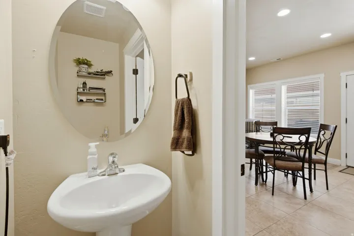 Pedestal sink with a polished chrome faucet and an oval wall mirror