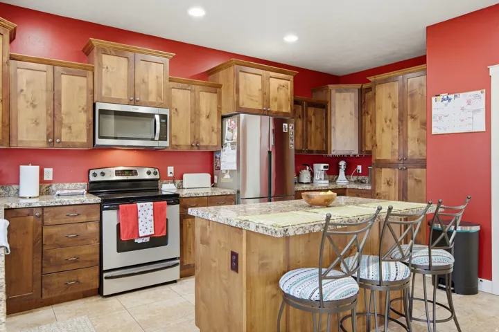 Kitchen featuring wood cabinetry, stainless steel appliances, and a central island with a granite countertop