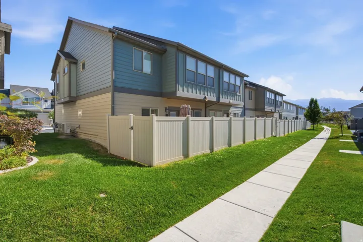 Exterior features include two-tone siding, a private patio area, and a light-toned privacy fence