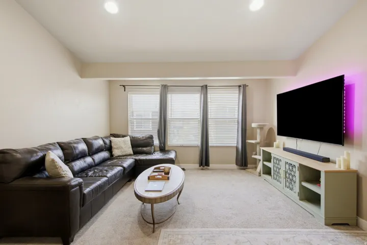 Carpeted living area featuring recessed lighting, multiple windows with blinds, and a built-in media console