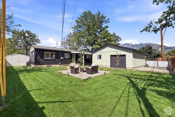 Spacious backyard featuring a large lawn, a detached storage shed, and a separate utility building with a roll-up door