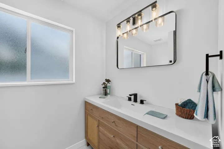 Modern bathroom featuring a wood-finish vanity with integrated sink, white countertop, and matte black fixtures
