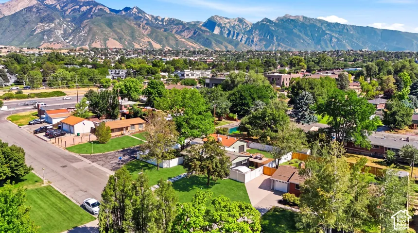 Residential neighborhood featuring mature trees, paved streets, and a mountainous backdrop