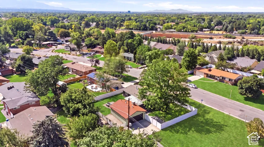 Expansive residential neighborhood featuring lush green lawns, mature trees, and a distant mountain range backdrop
