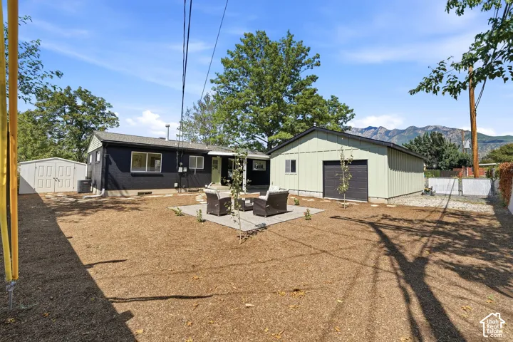 Expansive backyard featuring a large detached garage with a roll-up door, a separate storage shed, and a stone paver patio