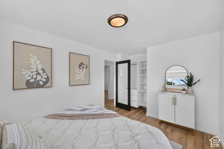Bedroom featuring wood-finish flooring, a contemporary flush-mount ceiling light, and white walls