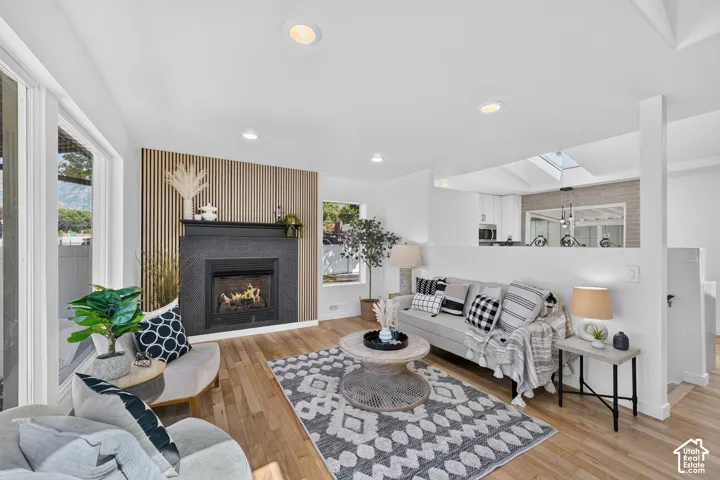 Living area featuring wood-finish flooring, a contemporary fireplace with a dark stone surround, and an accent wall with vertical slat detailing