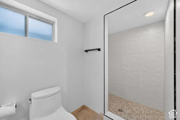 Walk-in shower featuring textured white tile walls and a pebble-finish floor