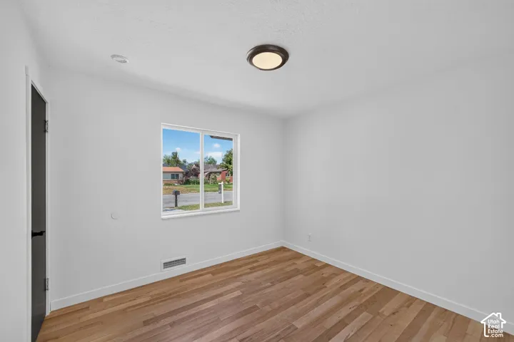 Interior room featuring light wood-finish flooring and a white baseboard trim