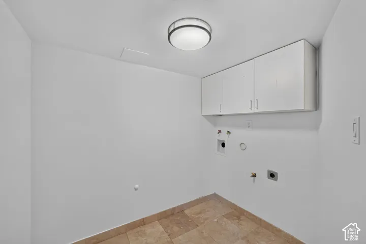 Utility space with light beige tile flooring, white walls, and a contemporary ceiling light fixture