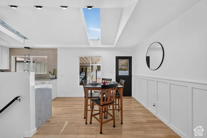 Open-concept living space with a large skylight, wood-finish flooring, and white paneling