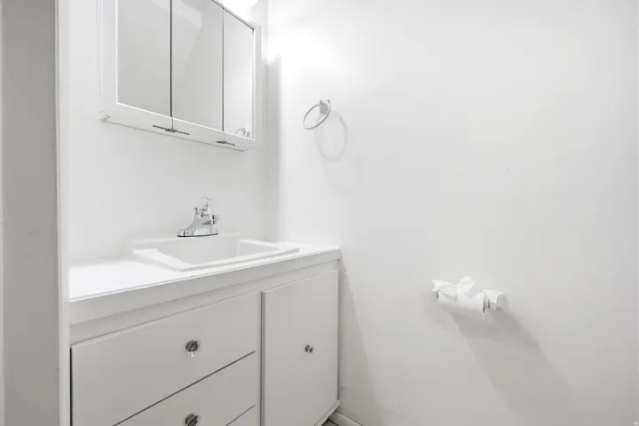 White vanity with an integrated sink, polished chrome faucet, and mirrored medicine cabinet