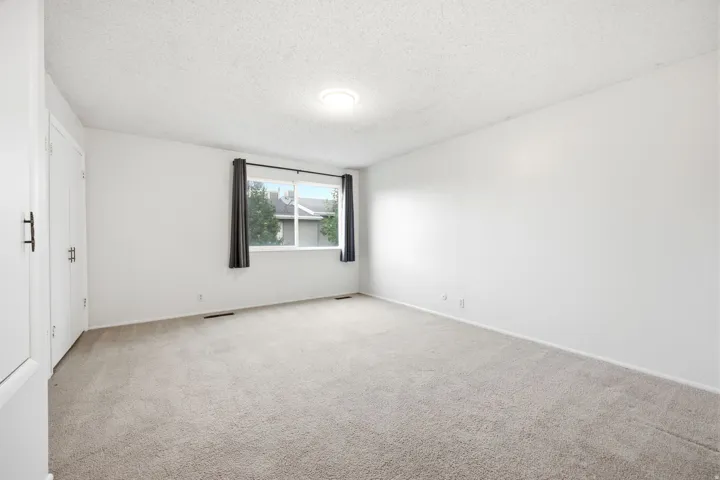 Carpeted room with a window featuring dark curtains, white walls, and brand new light fixture