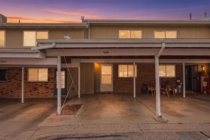 Multi-unit residential exterior featuring brick and siding facades, individual entry doors, and ground-level windows. This unit has 2 covered parking stalls. Most units only have 1.
