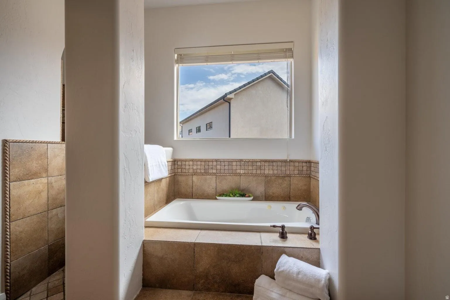 Built-in soaking tub featuring bronze fixtures and surrounding tilework