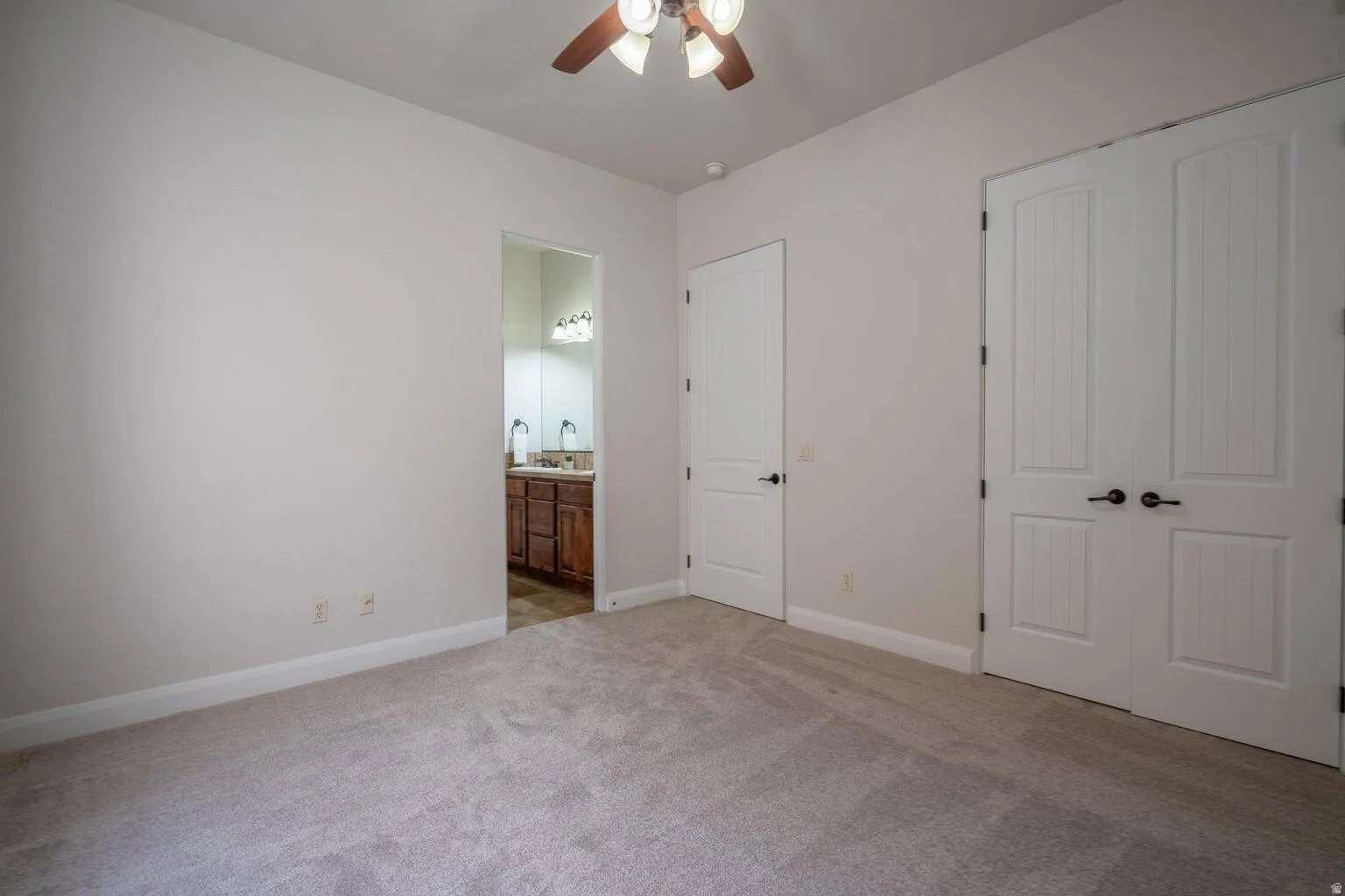 Spacious room featuring neutral carpeting, light-colored walls, and a ceiling fan with integrated lighting