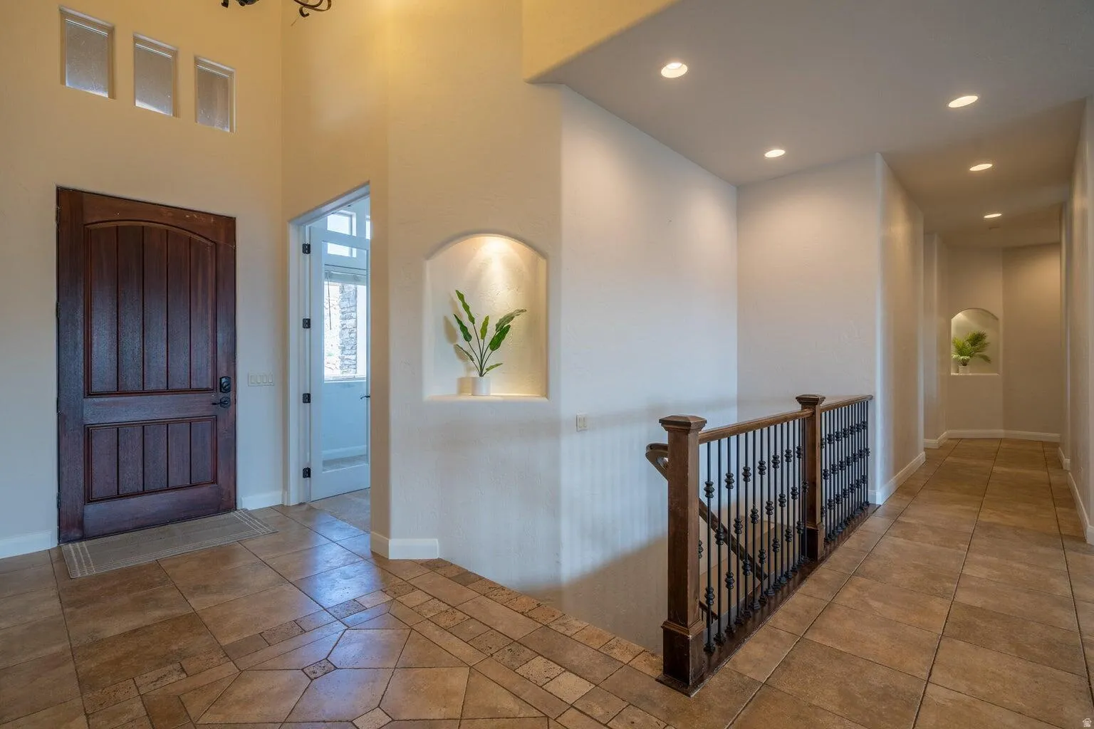 Entryway featuring a wood-panel door, decorative transom windows, and recessed niches with accent lighting