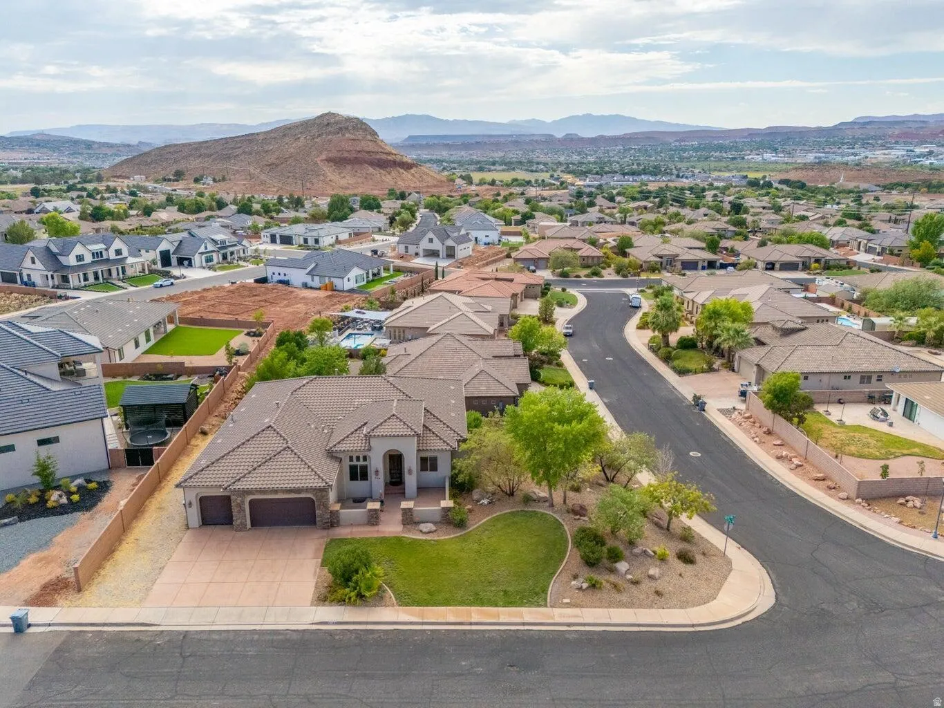 Southwestern-style residence featuring a tile roof, a stone and stucco exterior, an attached two-car garage, and a concrete driveway