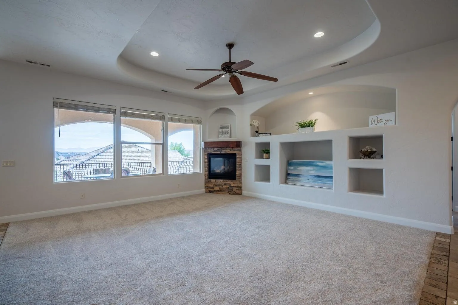Spacious living area featuring a tray ceiling with recessed lighting and a ceiling fan