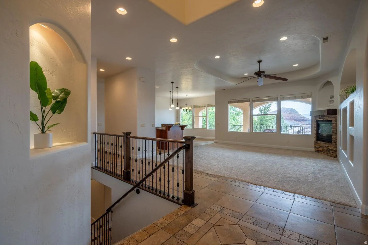 Spacious living area featuring a tray ceiling, recessed lighting, and a ceiling fan