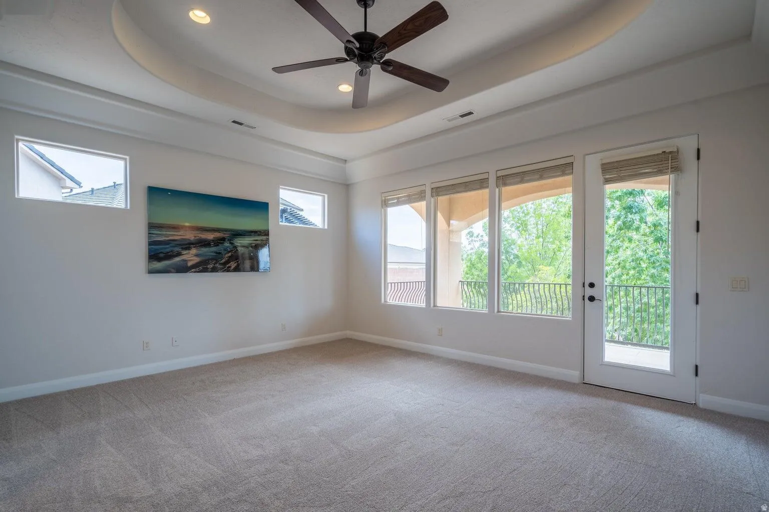 Room featuring an elegant tray ceiling with recessed lighting and a ceiling fan