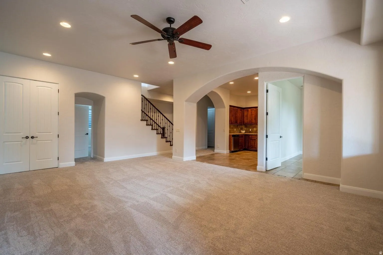 Spacious living area featuring neutral carpet flooring, recessed lighting, and a ceiling fan