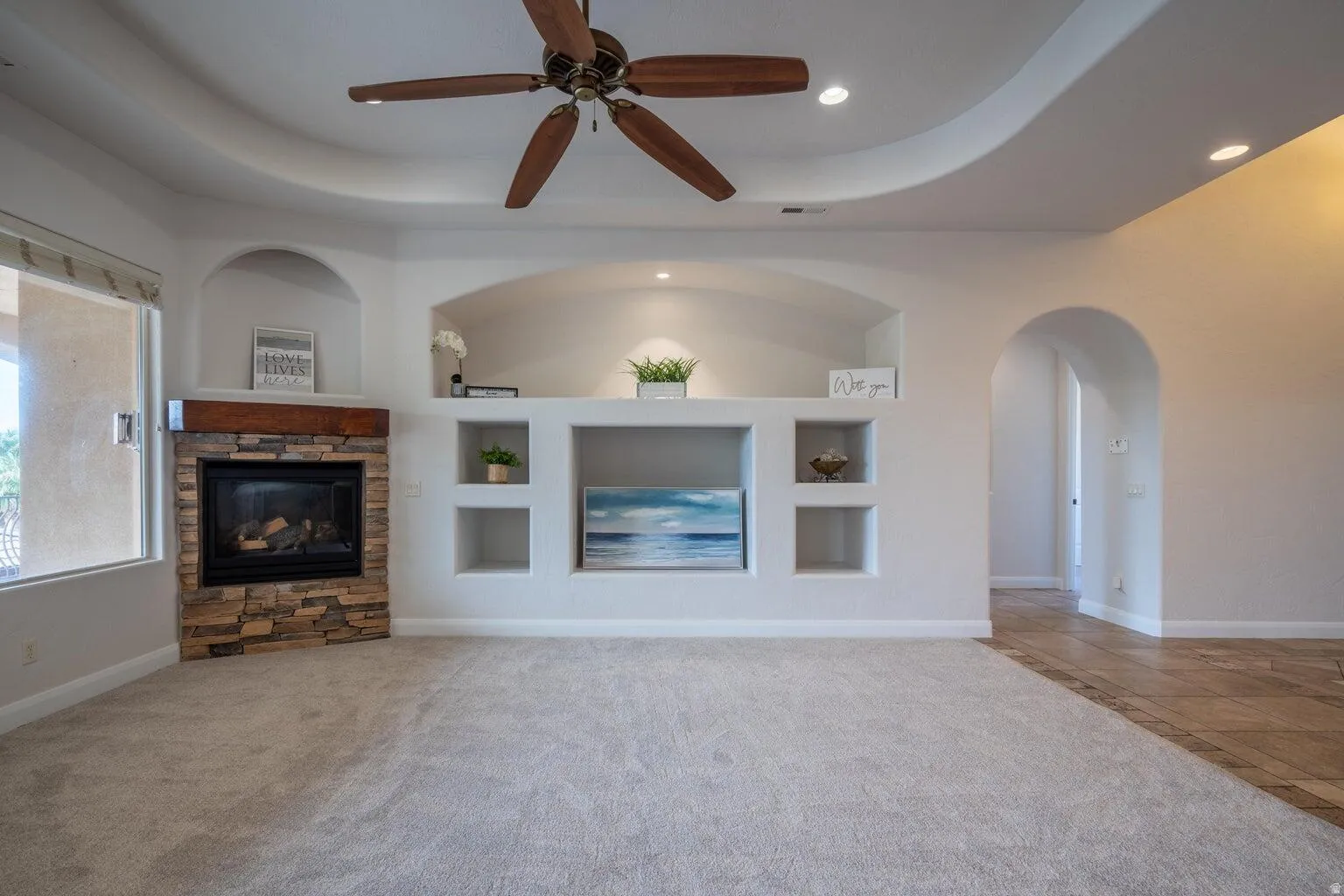 Living area featuring a corner fireplace with stone veneer surround and a wood mantel