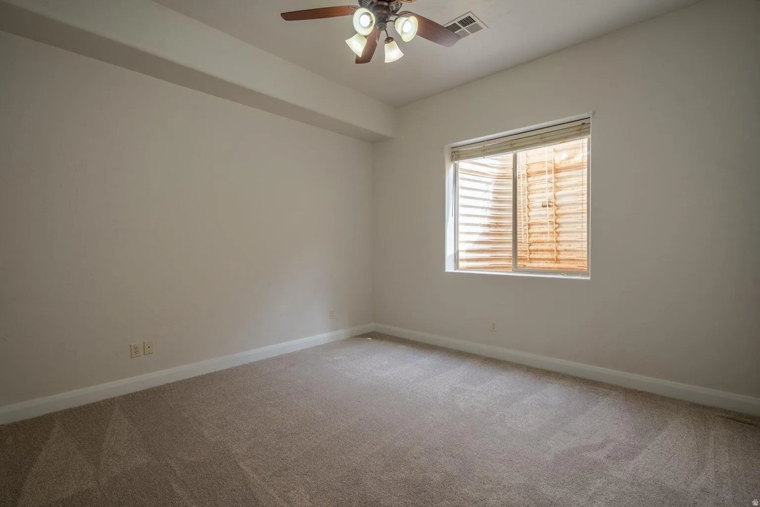 Carpeted interior space with a ceiling fan light fixture