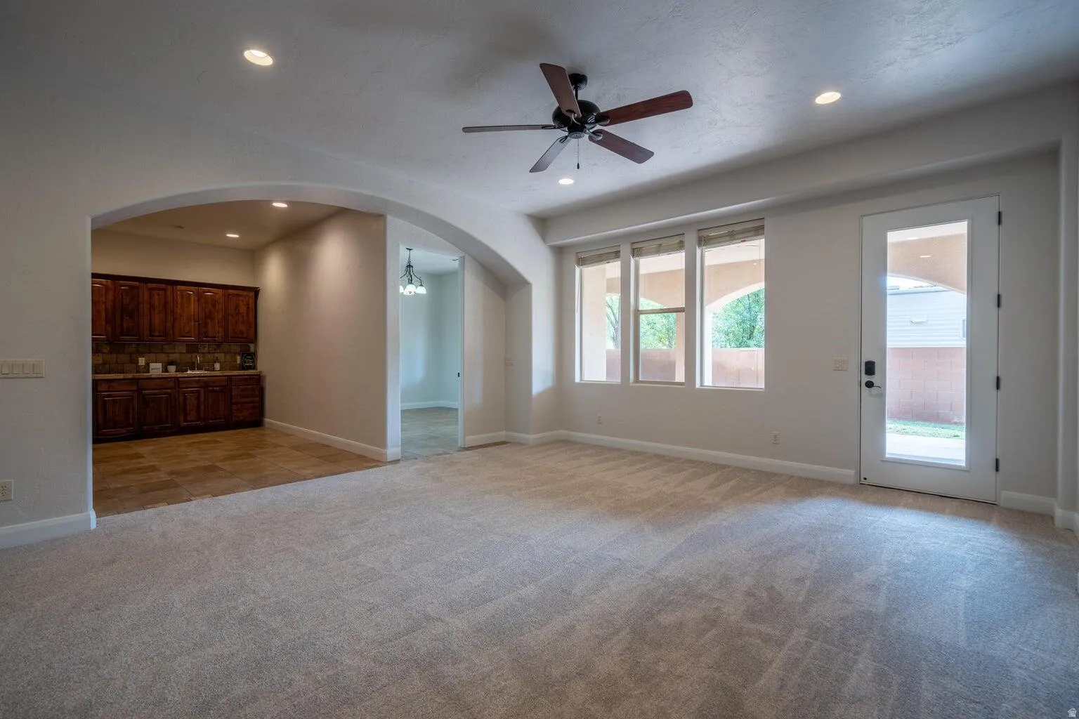 Spacious living area featuring neutral carpeting and recessed lighting