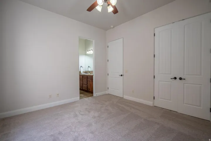 Carpeted interior room with an attached bathroom featuring a dual vanity and wood-finish cabinetry